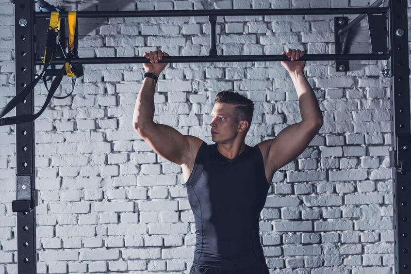 man with hands on pull up bar at the gym