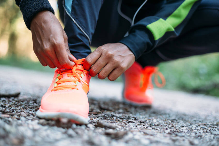 woman tying laces of running shoes before training