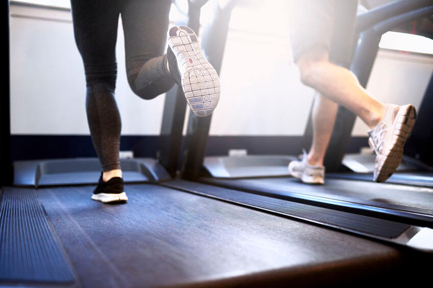 couple running on treadmill inside fitness gym