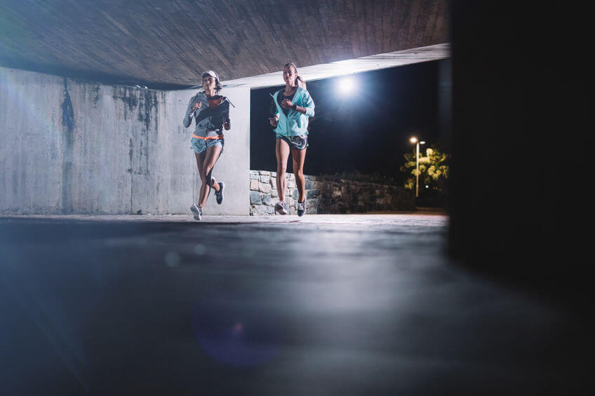 two female runners running together at night in city